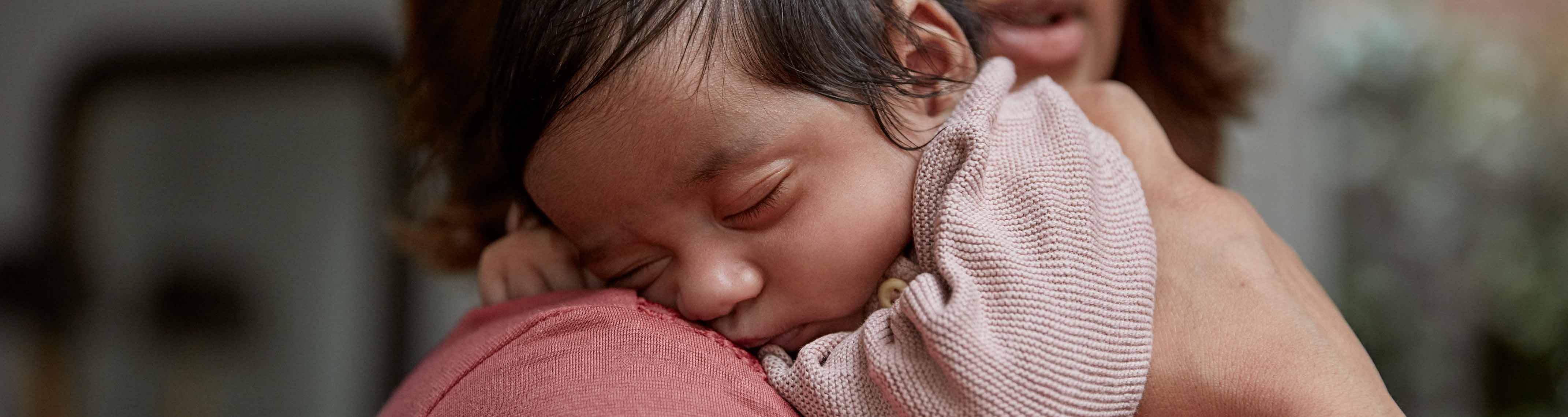 newborn sleeping on parent image